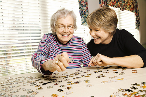 Elderly Mother and her daughter putting a puzzle together 
